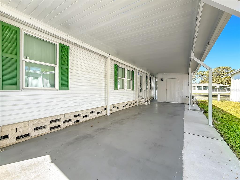 A covered concrete carport runs along the side of a white mobile home — 980 7TH STREET NW UNIT 43, LARGO, FL