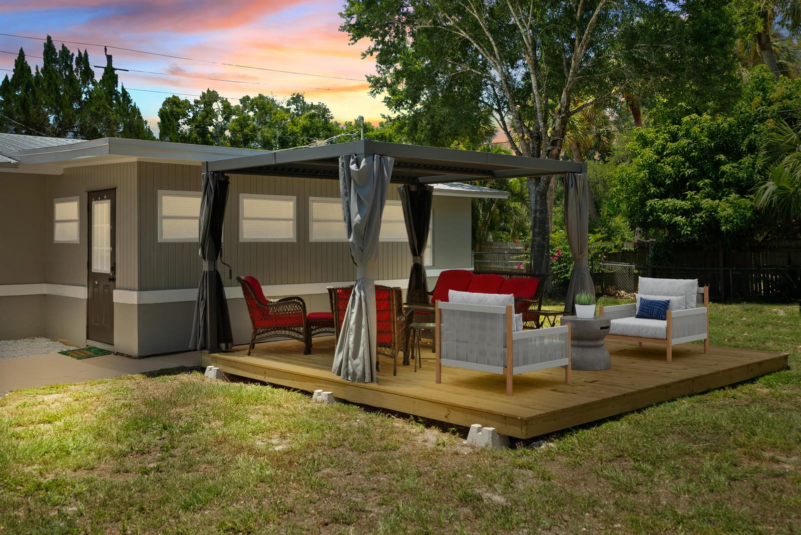A wooden deck with a gazebo and outdoor furniture sits in a backyard next to a house — 4220 Sunrise Boulevard, Fort Pierce FL 34982, FORT PIERCE, FL