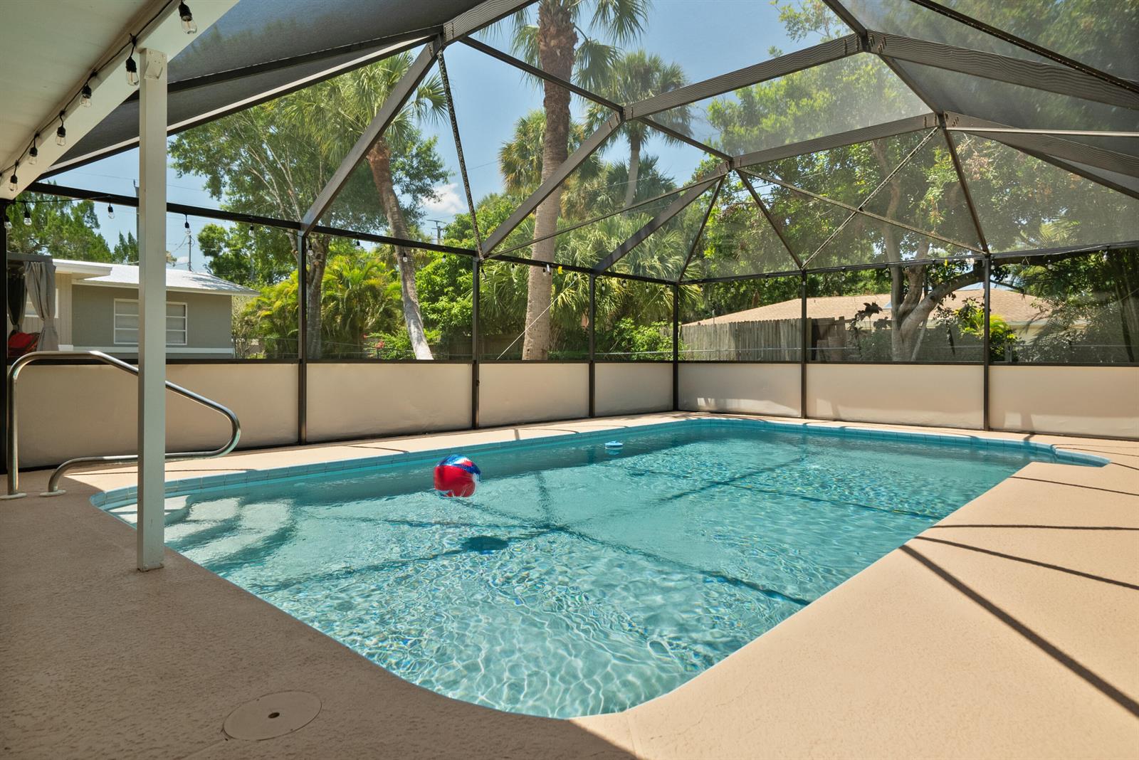A screened-in swimming pool with a beige deck and a beach ball in the water — 4220 Sunrise Boulevard, Fort Pierce FL 34982, FORT PIERCE, FL
