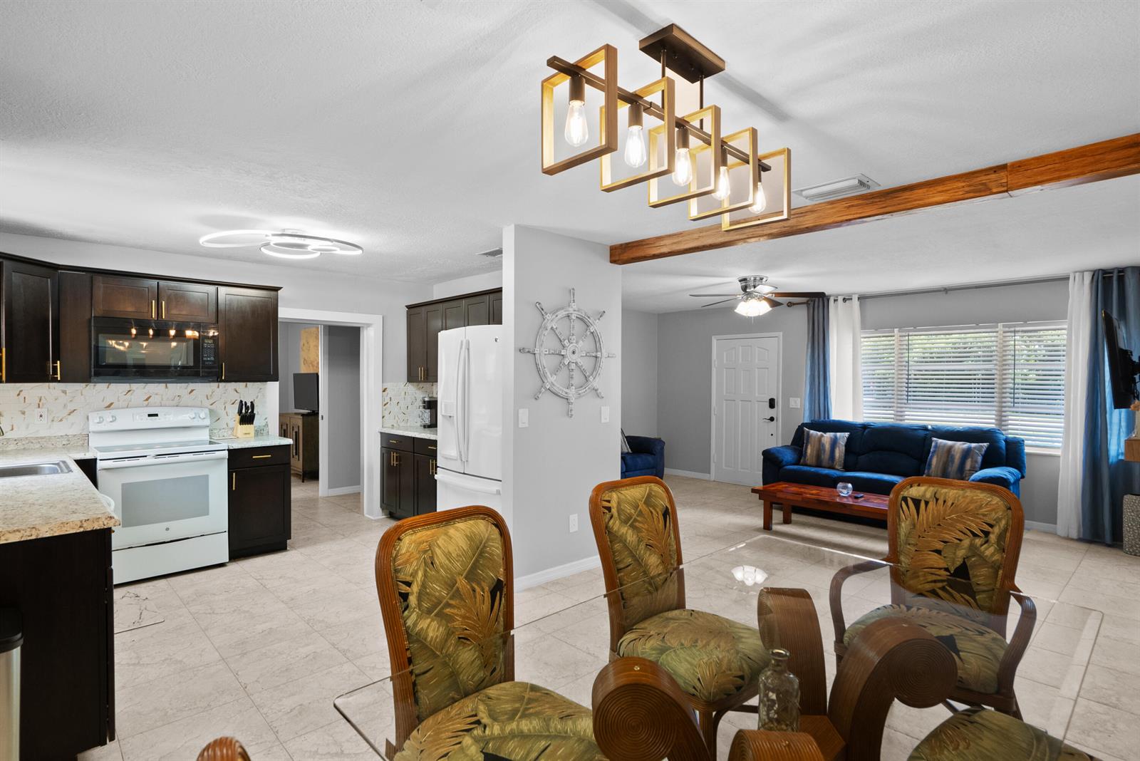 An open-concept kitchen and living area features dark wood cabinets, tile flooring, and a dining set — 4220 Sunrise Boulevard, Fort Pierce FL 34982, FORT PIERCE, FL