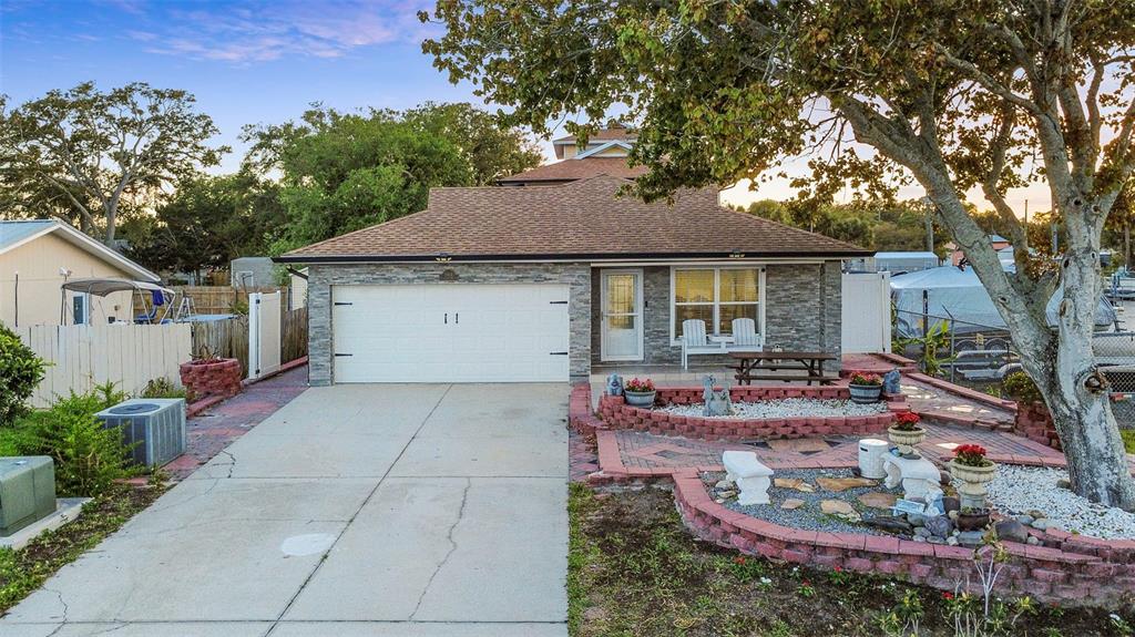 A single-story house with a stone facade, a two-car garage, and a tiered brick garden — 5414 RIVERSIDE DRIVE, PORT ORANGE, FL
