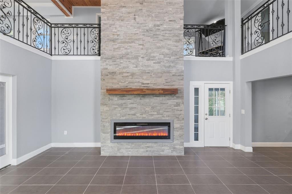 A living room features a stone fireplace, tiled floors, and a staircase with iron railings — 5414 RIVERSIDE DRIVE, PORT ORANGE, FL