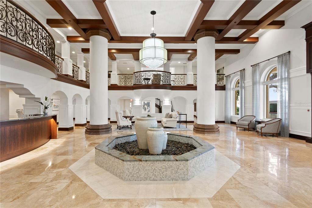 A grand lobby features a central stone fountain, large white columns, and a mezzanine balcony — 4201 BAYSHORE BOULEVARD UNIT 2101, TAMPA, FL