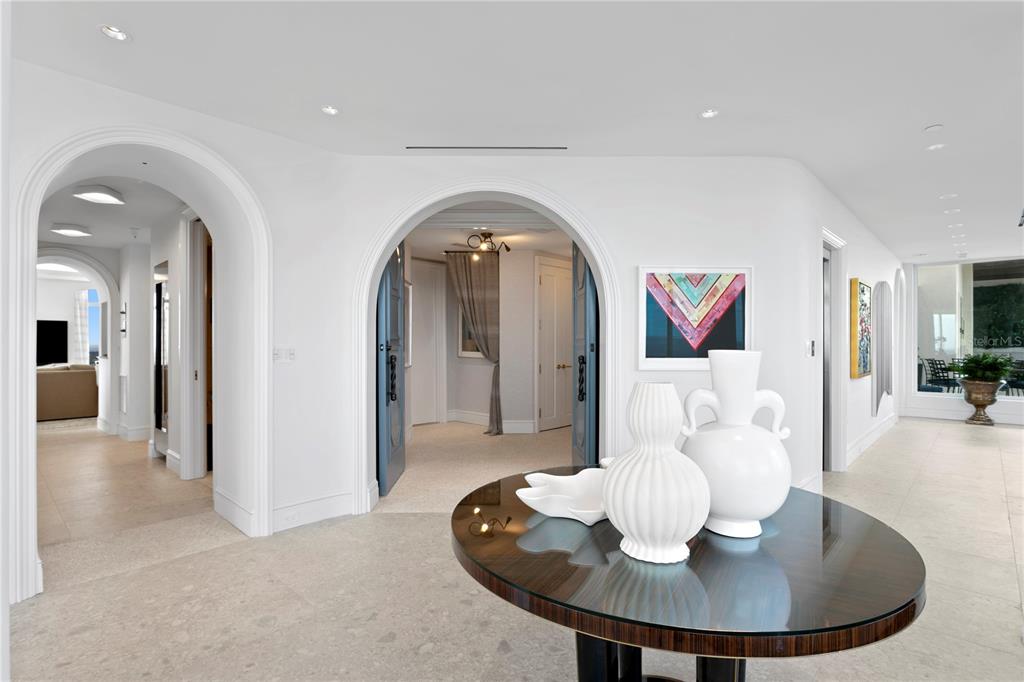 A foyer features arched doorways, white walls, a round table with vases, and tile flooring — 4201 BAYSHORE BOULEVARD UNIT 2101, TAMPA, FL