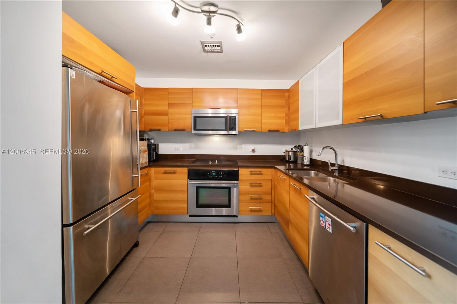 A galley kitchen features wood cabinetry, stainless steel appliances, and dark countertops — 3301 NE 1st Ave # M0308, Miami FL 33137, MIAMI, FL