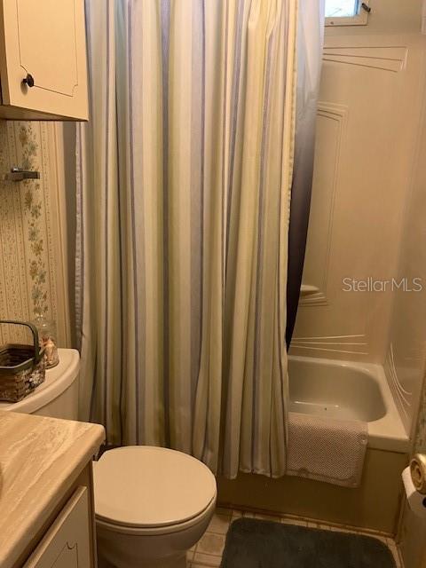 A bathroom features a toilet, a vanity, and a shower-tub combination with a striped curtain — 3201 BREWSTER DRIVE, HOLIDAY, FL