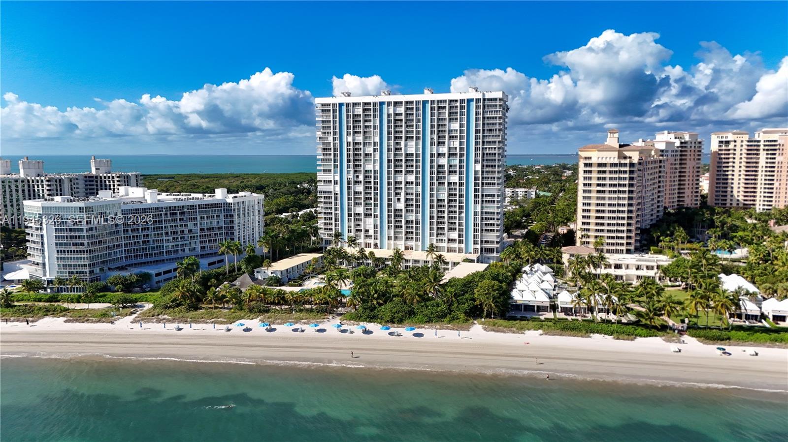 An aerial view shows several high-rise residential buildings situated along a sandy beach — 881 Ocean Dr, Key Biscayne FL 33149, KEY BISCAYNE, FL