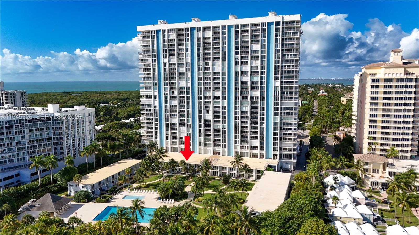 An aerial view shows a tall residential tower with a red arrow pointing toward its base — 881 Ocean Dr, Key Biscayne FL 33149, KEY BISCAYNE, FL