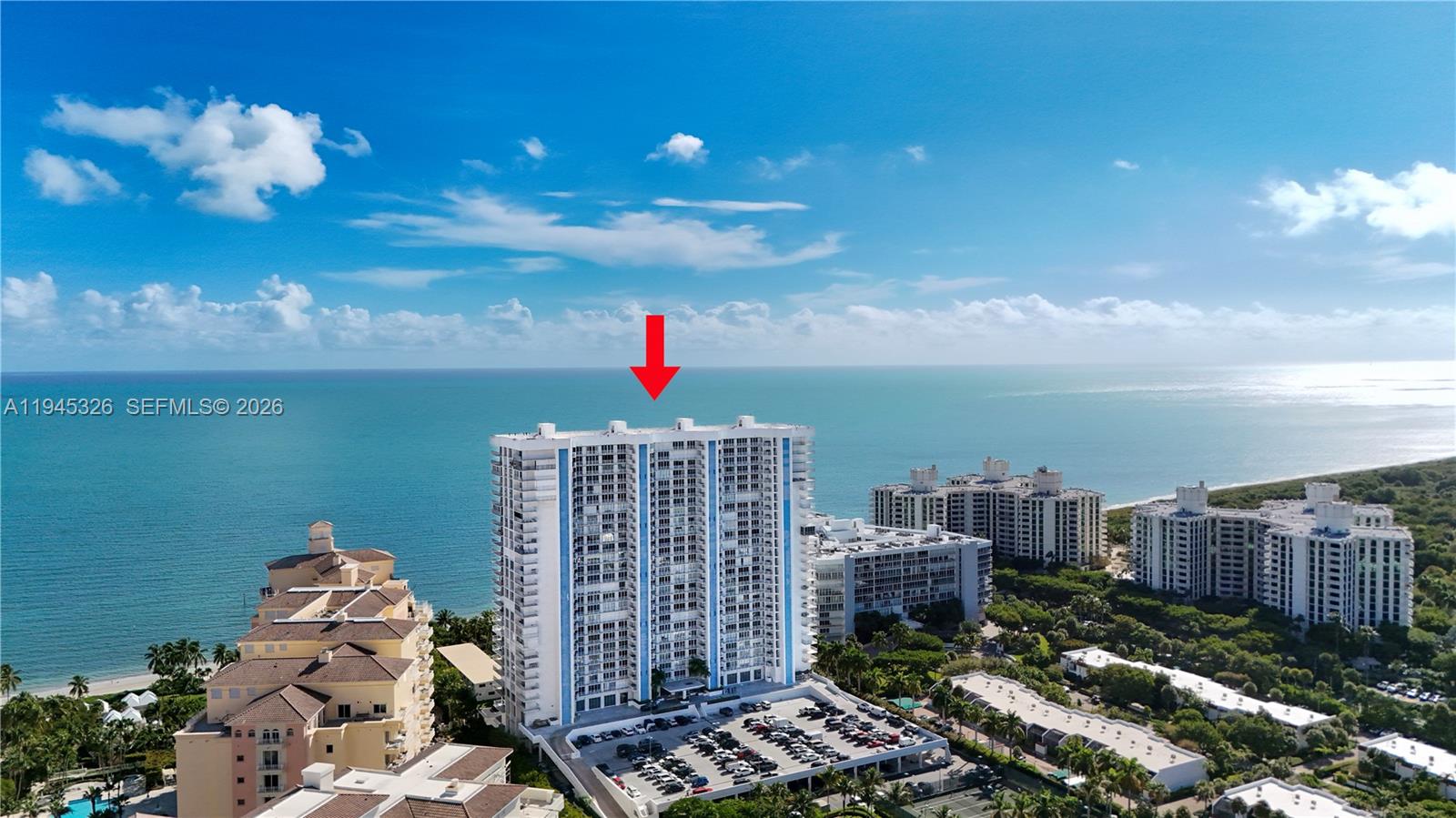 An aerial view shows a tall residential building situated along a coastline by the ocean — 881 Ocean Dr, Key Biscayne FL 33149, KEY BISCAYNE, FL