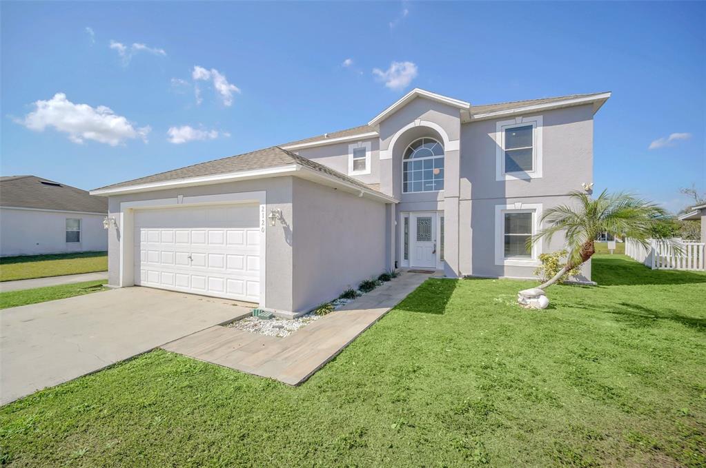 A two-story house with a gray stucco exterior, a white garage door, and a front lawn — 2120 MARISOL LOOP, KISSIMMEE, FL