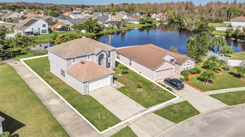 An aerial view shows a two-story suburban house with a white outline on its lot — 2120 MARISOL LOOP, KISSIMMEE, FL