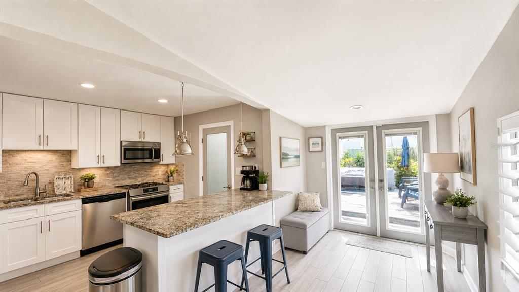 A kitchen with white cabinets, granite countertops, and a breakfast bar with two stools — 3606 S RENELLIE DRIVE, TAMPA, FL