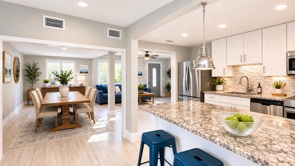A kitchen with granite countertops and white cabinets opens into a dining and living area — 3606 S RENELLIE DRIVE, TAMPA, FL