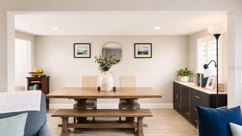 A dining room features a wooden table, bench seating, two chairs, and a sideboard cabinet — 3606 S RENELLIE DRIVE, TAMPA, FL