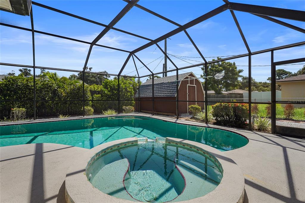 A screened-in pool and hot tub area with a small storage shed in the backyard — 4215 PANDORA ROAD, VENICE, FL
