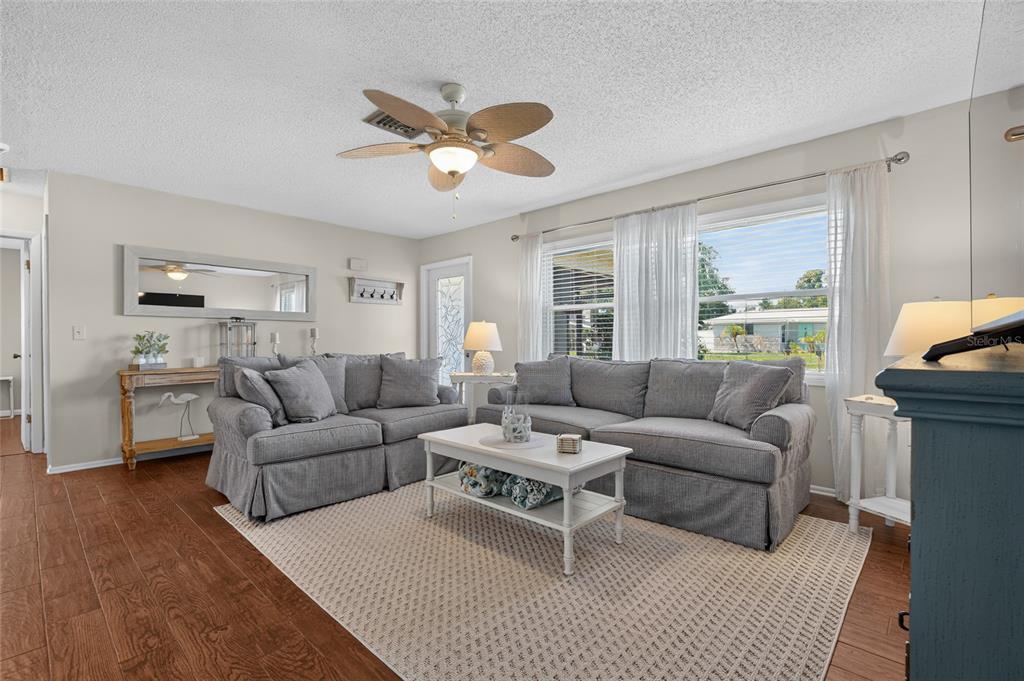 A living room features gray sofas, a white coffee table, and wood-look flooring — 4215 PANDORA ROAD, VENICE, FL