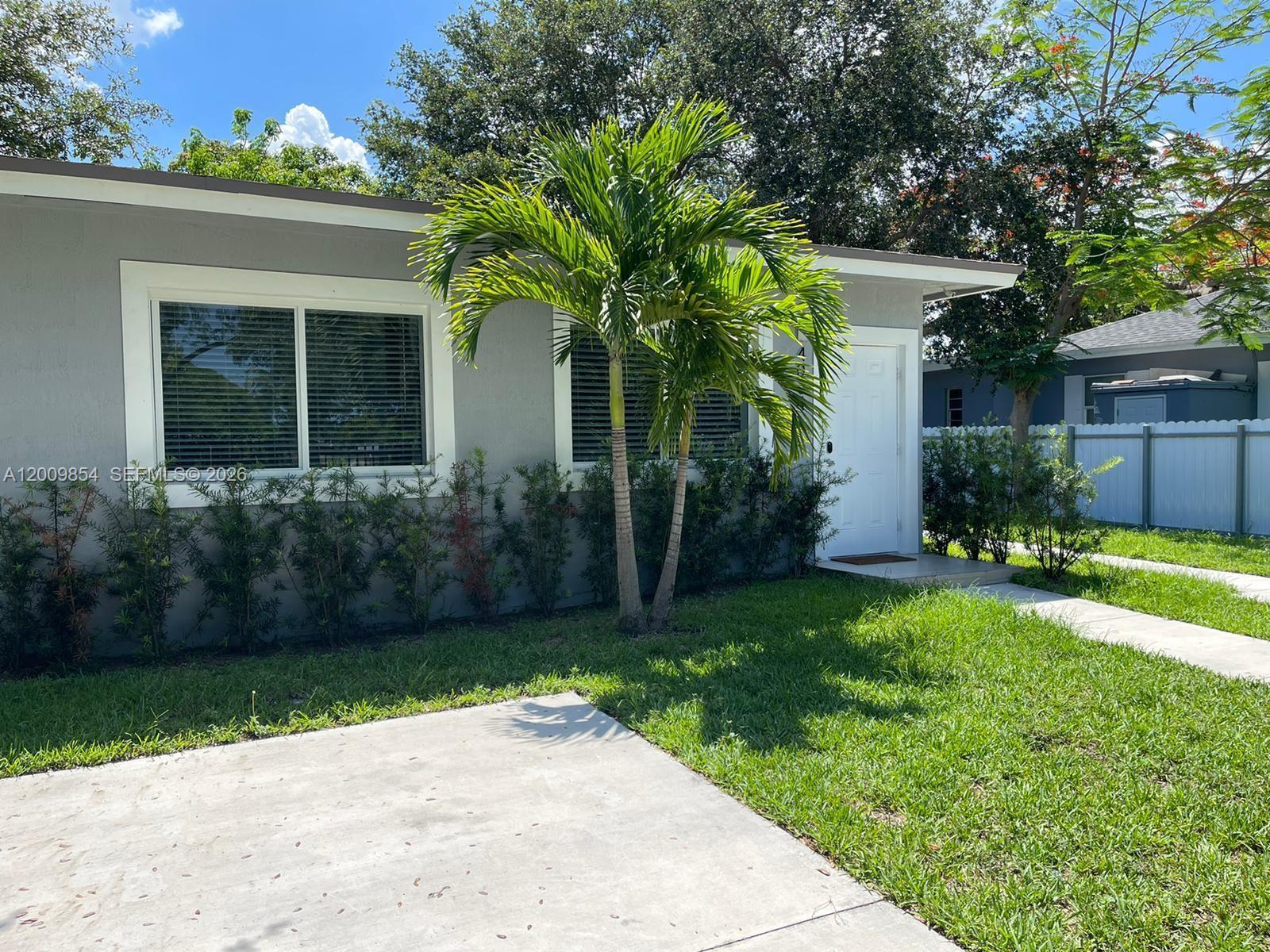 A gray house exterior features a palm tree, white trim, and a concrete walkway — 4034 NW 23rd Ave # 0, Miami FL 33142, MIAMI, FL