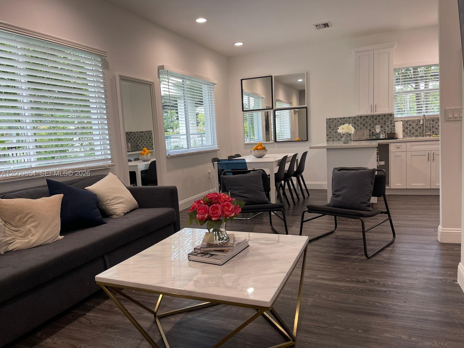 A modern living room and kitchen area with dark wood floors and a marble coffee table — 4034 NW 23rd Ave # 0, Miami FL 33142, MIAMI, FL