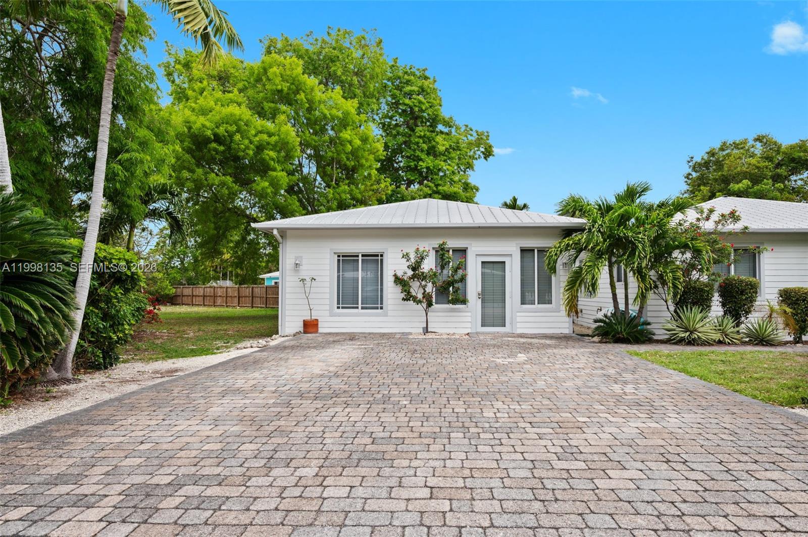A white single-story house with a paved driveway and palm trees under a blue sky — 4 Transylvania Ave # B, Key Largo FL 33037, KEY LARGO, FL