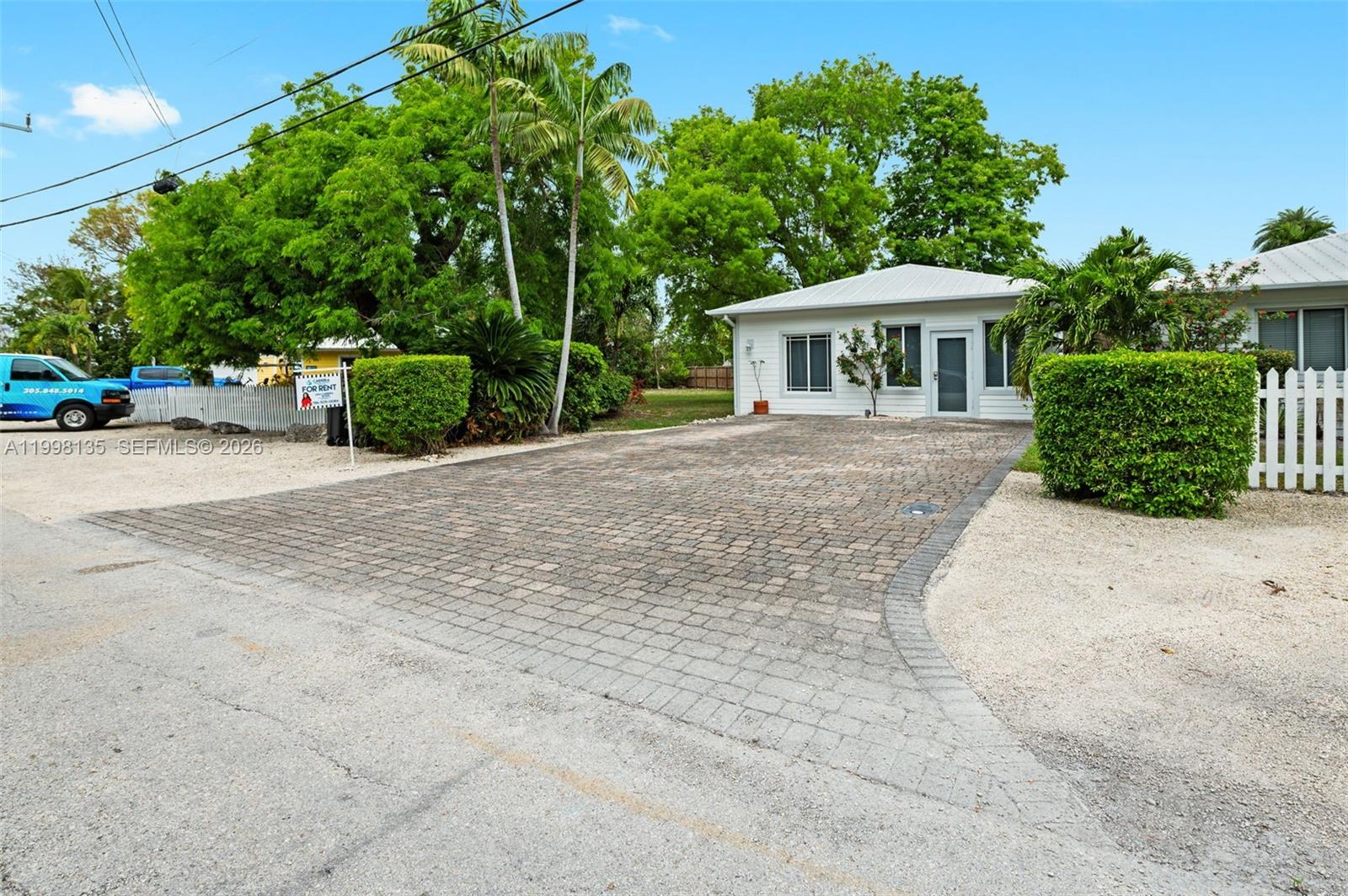 A white single-story house features a paved driveway and a manicured hedge in the front — 4 Transylvania Ave # B, Key Largo FL 33037, KEY LARGO, FL