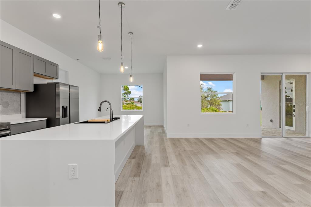 A modern kitchen features a white island, gray cabinets, and light wood-look flooring — 13514 KEYSTONE BOULEVARD, PORT CHARLOTTE, FL