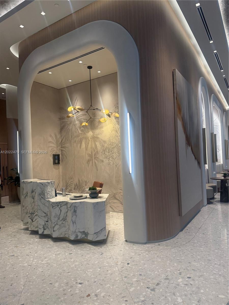 A modern reception area features a marble desk, arched wall alcoves, and a palm-patterned mural — 77 SE 5st # 2306, Miami FL 33131, MIAMI, FL