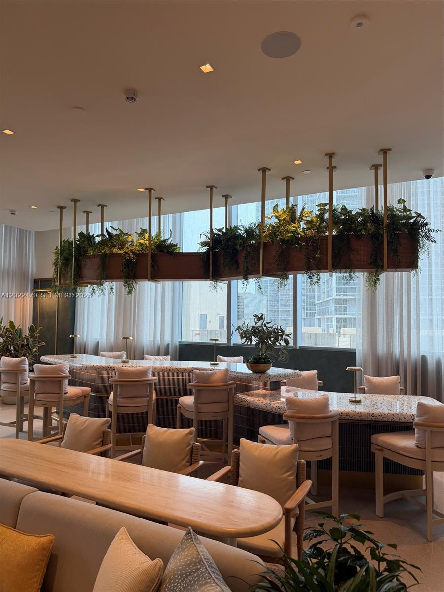 A modern lounge features a curved terrazzo bar, hanging planters, and light-colored upholstered seating — 77 SE 5st # 2306, Miami FL 33131, MIAMI, FL