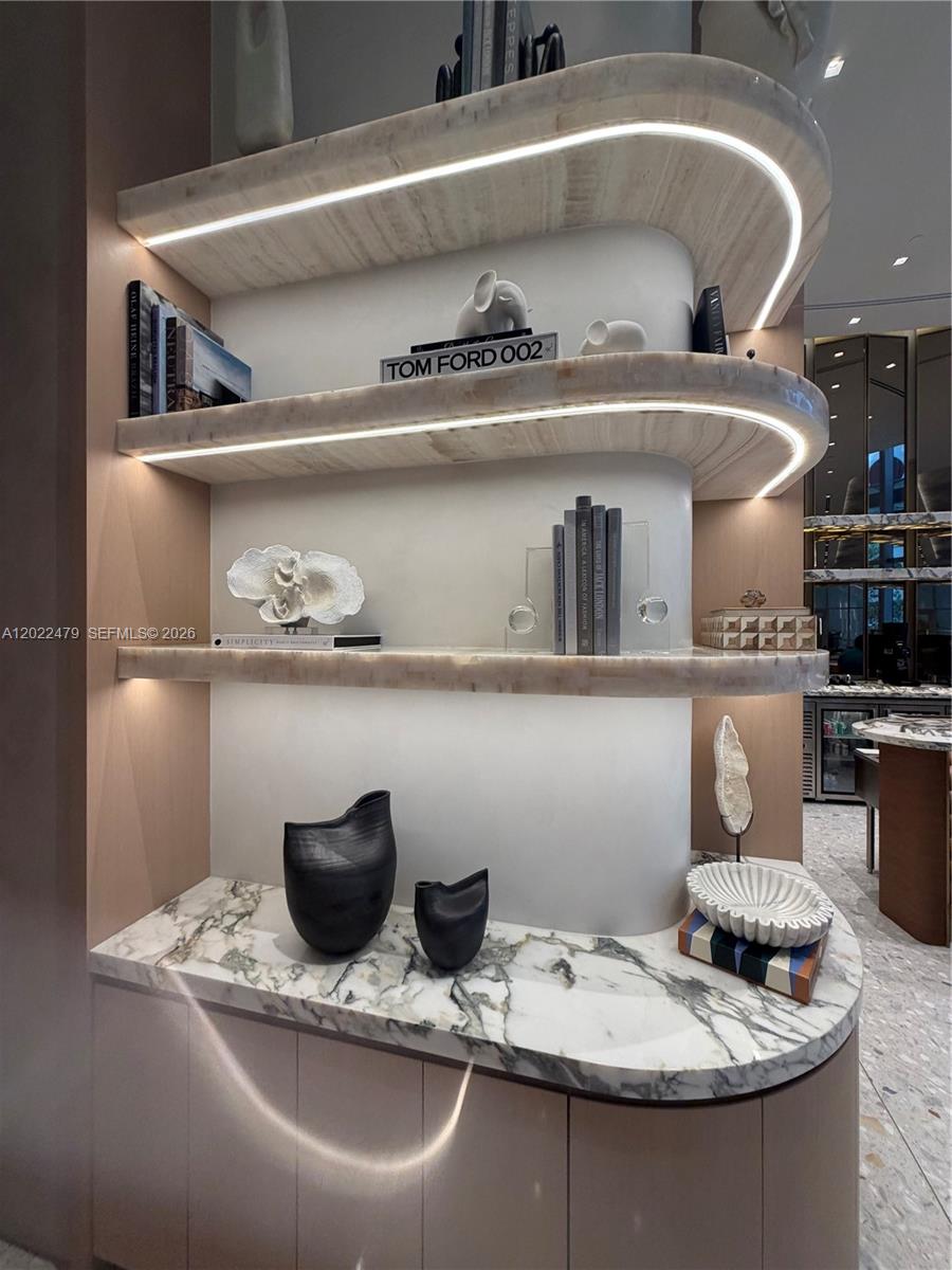 A curved marble shelving unit with integrated LED lighting sits above a marble-topped cabinet — 77 SE 5st # 2306, Miami FL 33131, MIAMI, FL