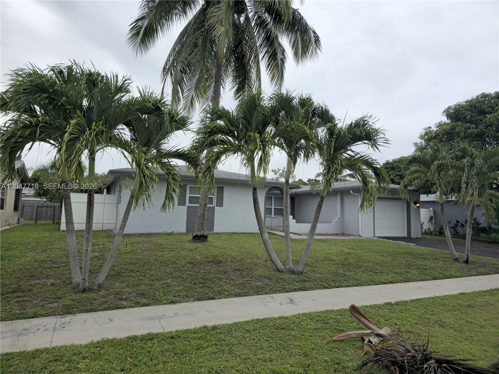 A single-story gray house with a garage and palm trees in the front yard — 7771 NW 46th St, Lauderhill FL 33351, LAUDERHILL, FL