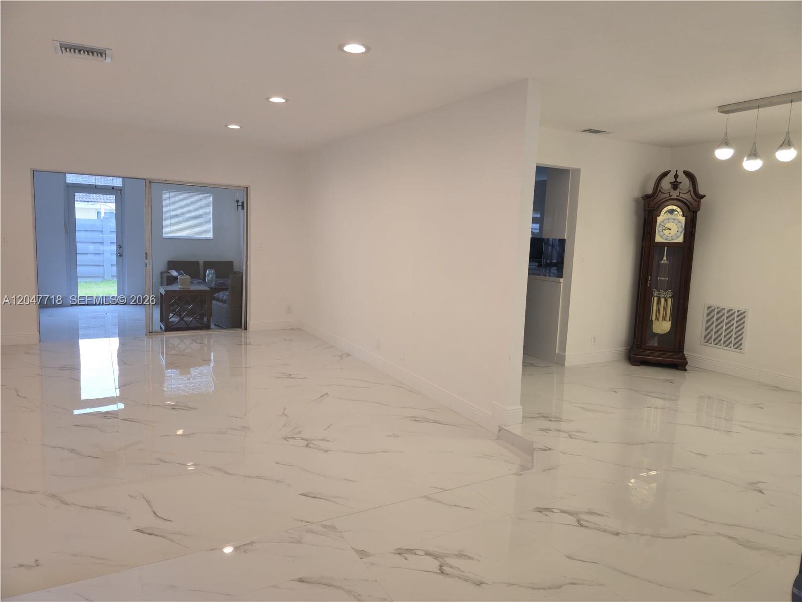 A bright room features white marble-look tile flooring, recessed lighting, and a tall grandfather clock — 7771 NW 46th St, Lauderhill FL 33351, LAUDERHILL, FL