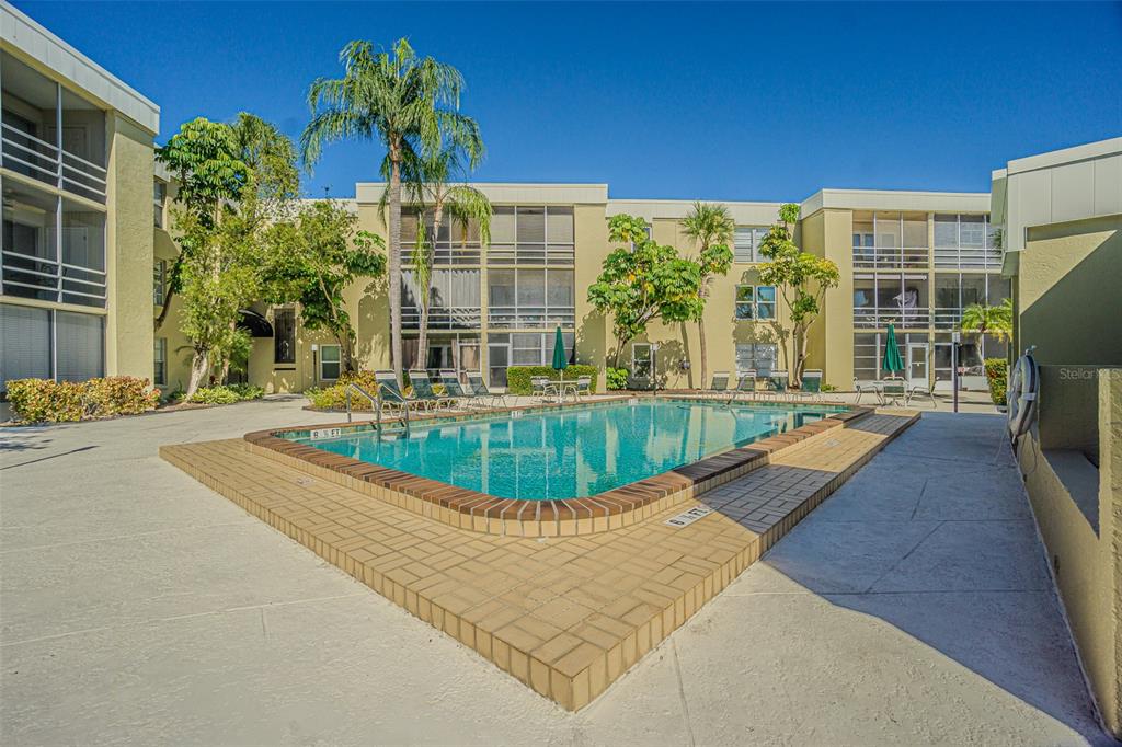 A rectangular swimming pool sits in a courtyard surrounded by multi-story apartment buildings — 2302 S MANHATTAN AVENUE UNIT 219, TAMPA, FL