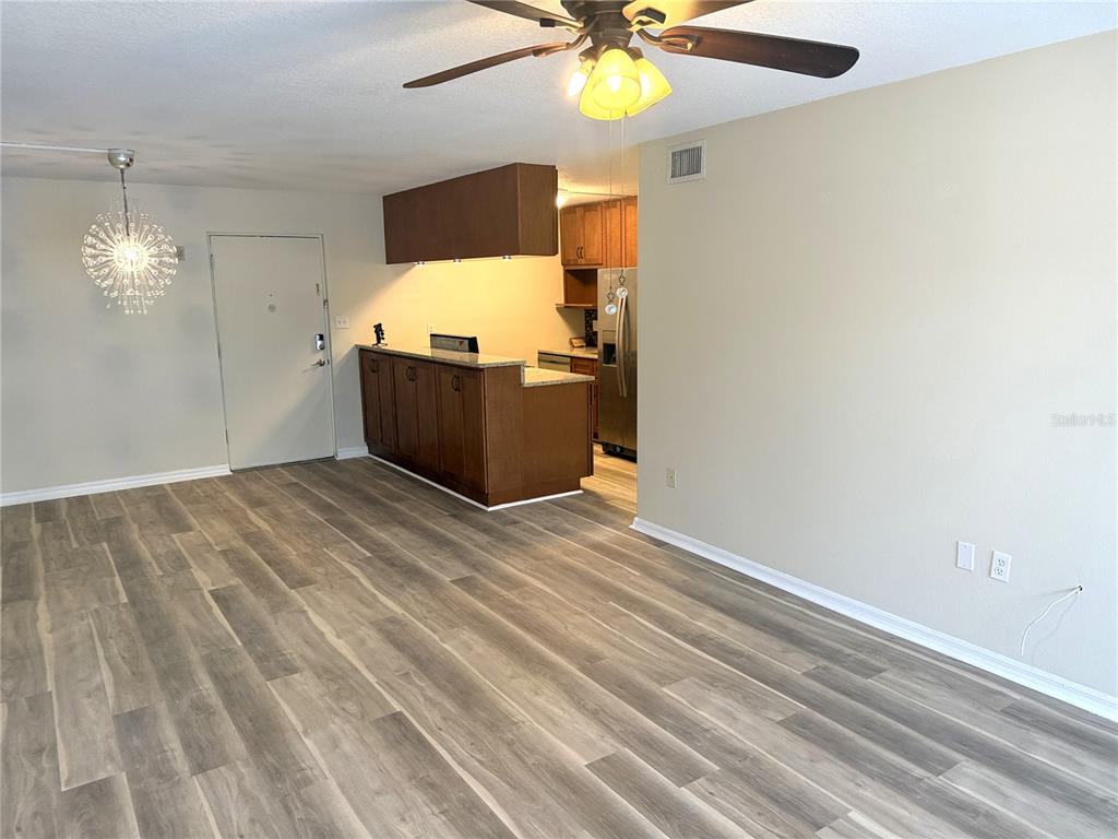 An open-concept living area features wood-look flooring, a kitchen with dark cabinets, and a ceiling fan — 2302 S MANHATTAN AVENUE UNIT 219, TAMPA, FL