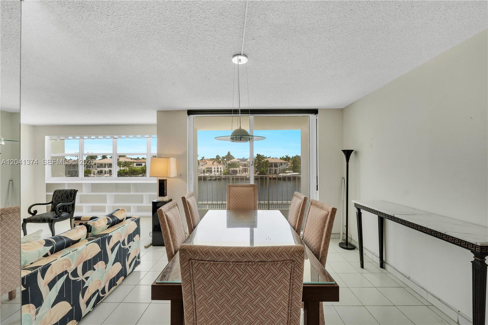 A dining area with a glass-topped table and chairs overlooks a canal and residential homes — 1410 S Ocean Dr # 304, Hollywood FL 33019, HOLLYWOOD, FL