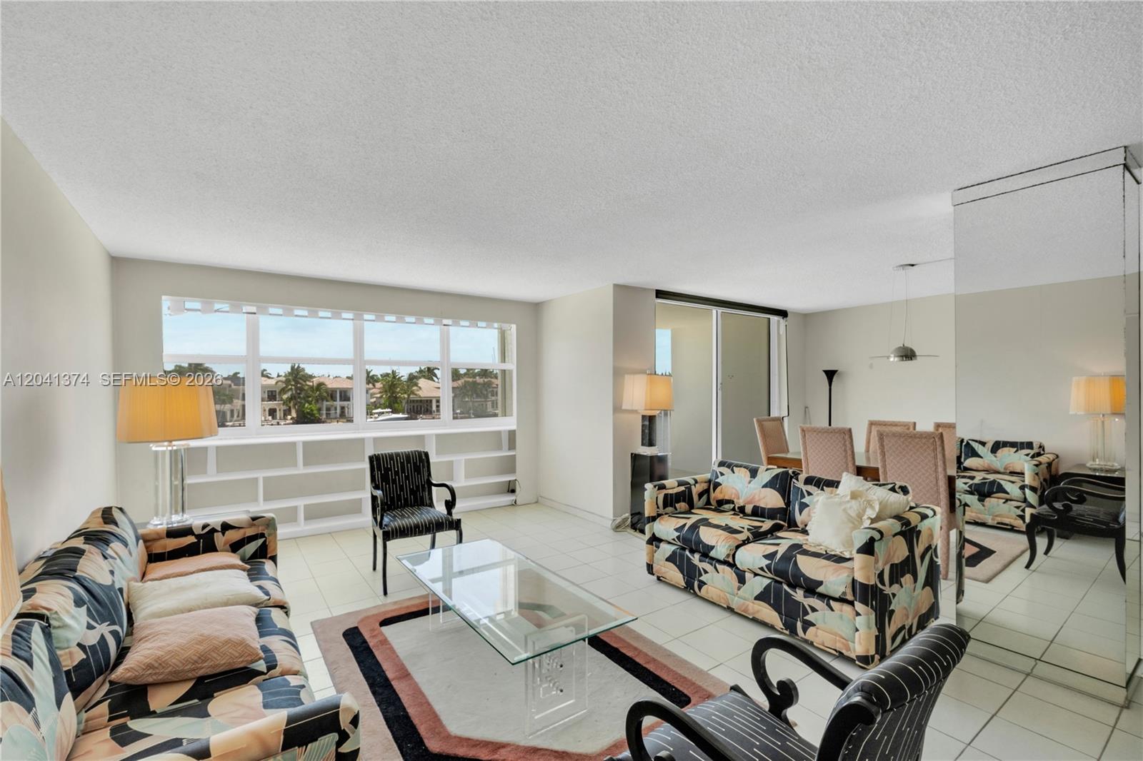 A living and dining area features tiled floors, patterned sofas, and a large window view — 1410 S Ocean Dr # 304, Hollywood FL 33019, HOLLYWOOD, FL