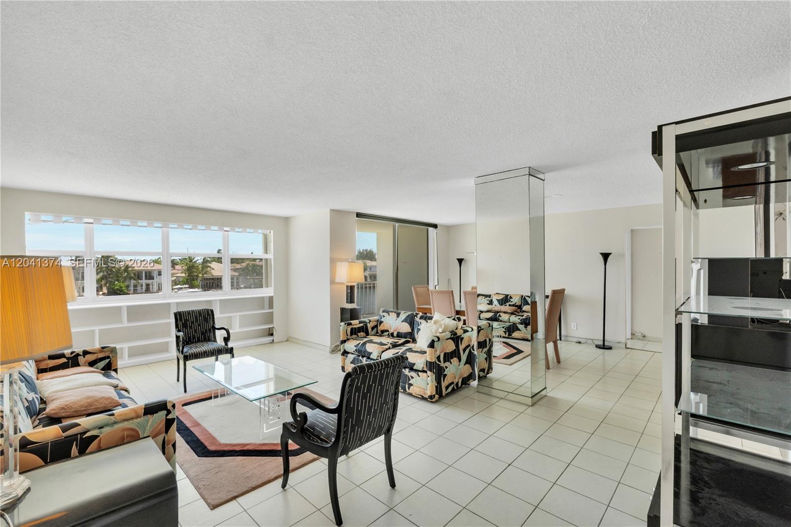 A living and dining area features tiled floors, a mirrored column, and large windows — 1410 S Ocean Dr # 304, Hollywood FL 33019, HOLLYWOOD, FL