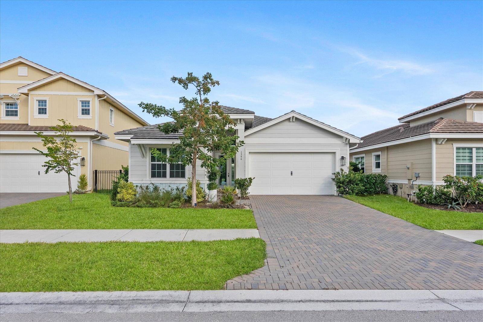 A single-story house with a white garage, paved driveway, and a small front lawn — 1346 Harvester Crossing, Loxahatchee FL 33470, LOXAHATCHEE, FL