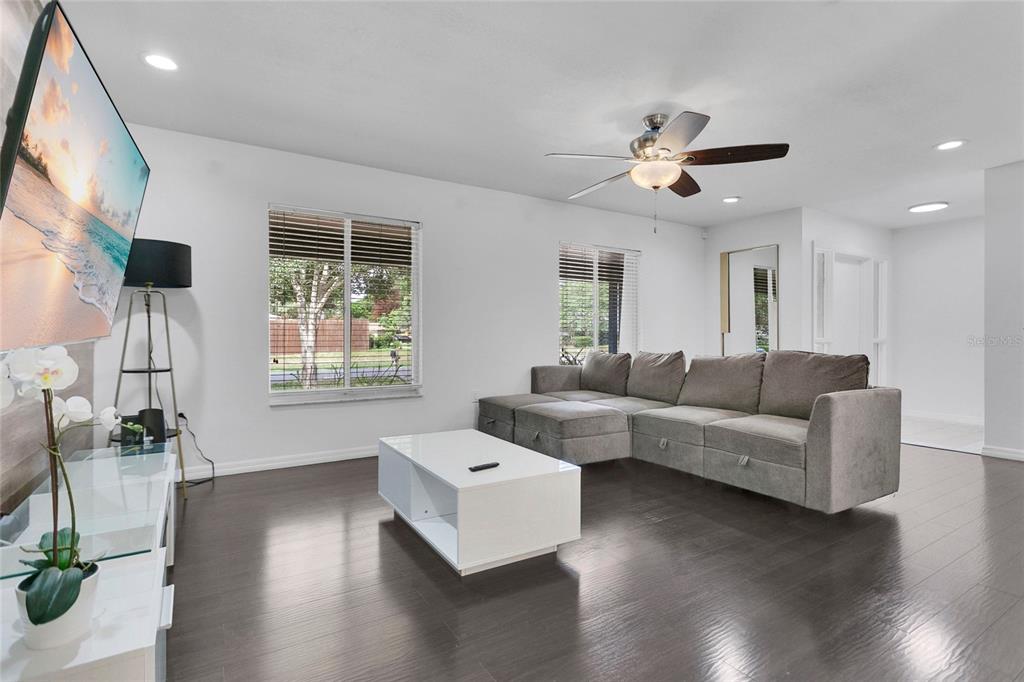 A living room features a grey sectional sofa, white coffee table, and dark wood flooring — 8644 SANDBERRY BOULEVARD, ORLANDO, FL
