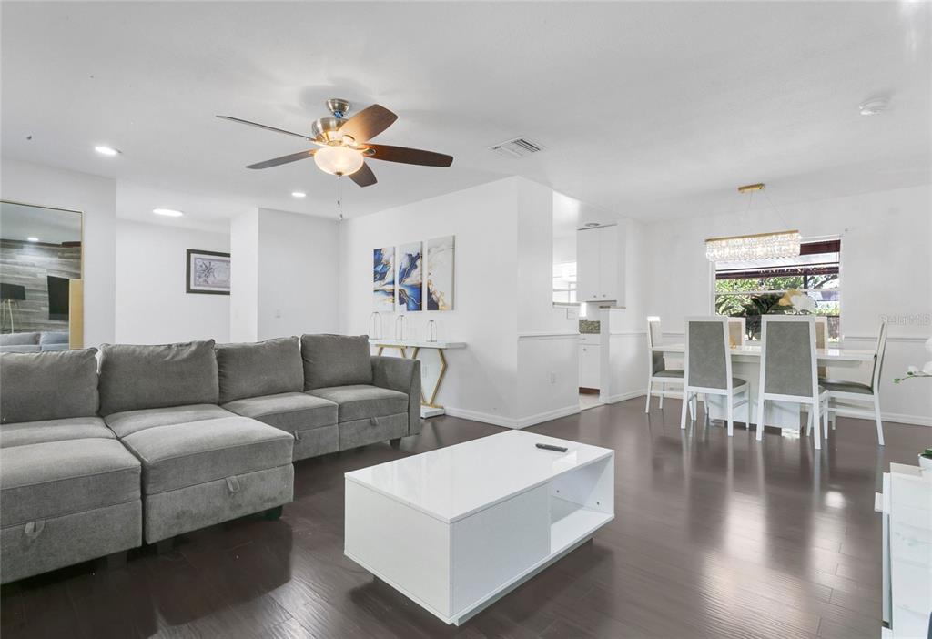 A living room and dining area feature dark wood floors, a gray sectional, and white furniture — 8644 SANDBERRY BOULEVARD, ORLANDO, FL