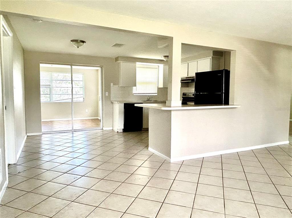 A tiled living area opens to a kitchen with a breakfast bar and sliding glass doors — 4653 DARLINGTON ROAD, HOLIDAY, FL