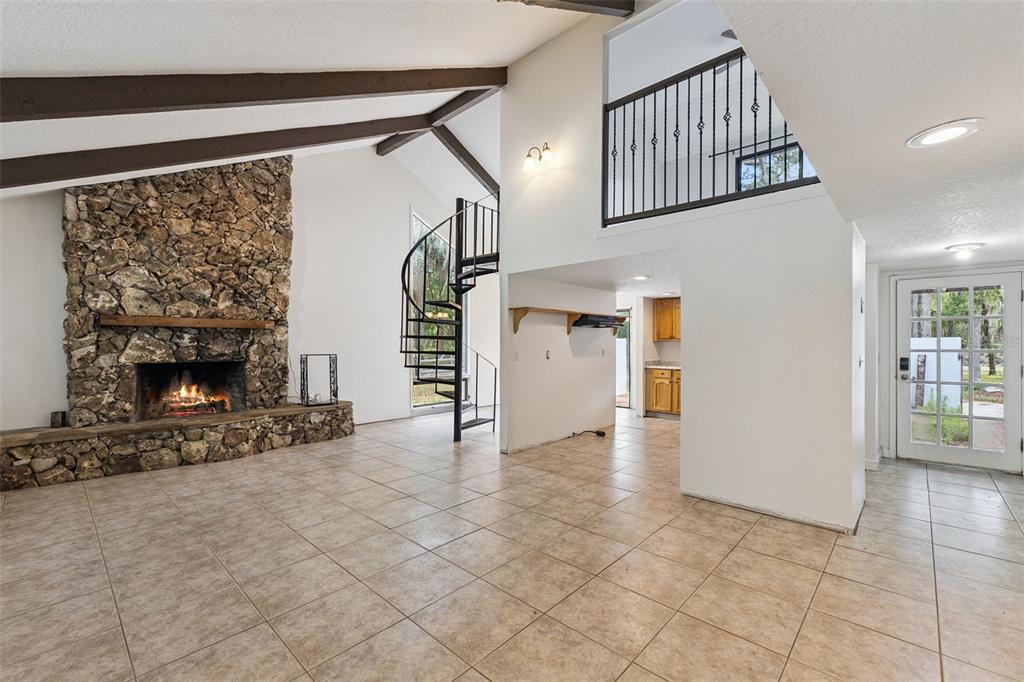 A living room features a stone fireplace, spiral staircase, tile flooring, and a loft area — 1142 BUCKLES ROAD, PIERSON, FL