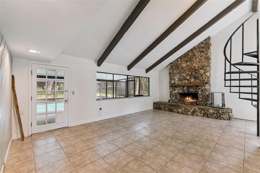 A living room features tile floors, a stone fireplace, exposed ceiling beams, and a spiral staircase — 1142 BUCKLES ROAD, PIERSON, FL
