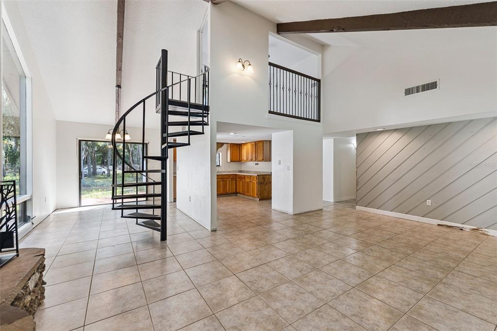 A living room features a spiral staircase, tile flooring, vaulted ceilings, and an adjacent kitchen — 1142 BUCKLES ROAD, PIERSON, FL