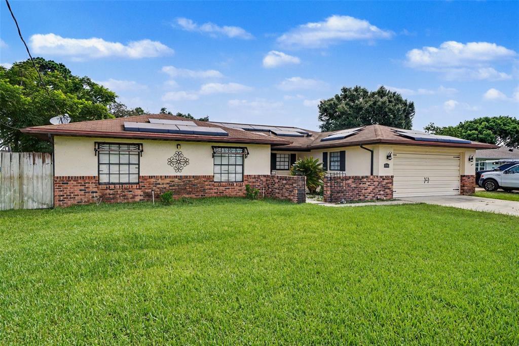 A single-story house with a brick facade, solar panels on the roof, and a garage — 1180 BALFOUR DRIVE, DELTONA, FL