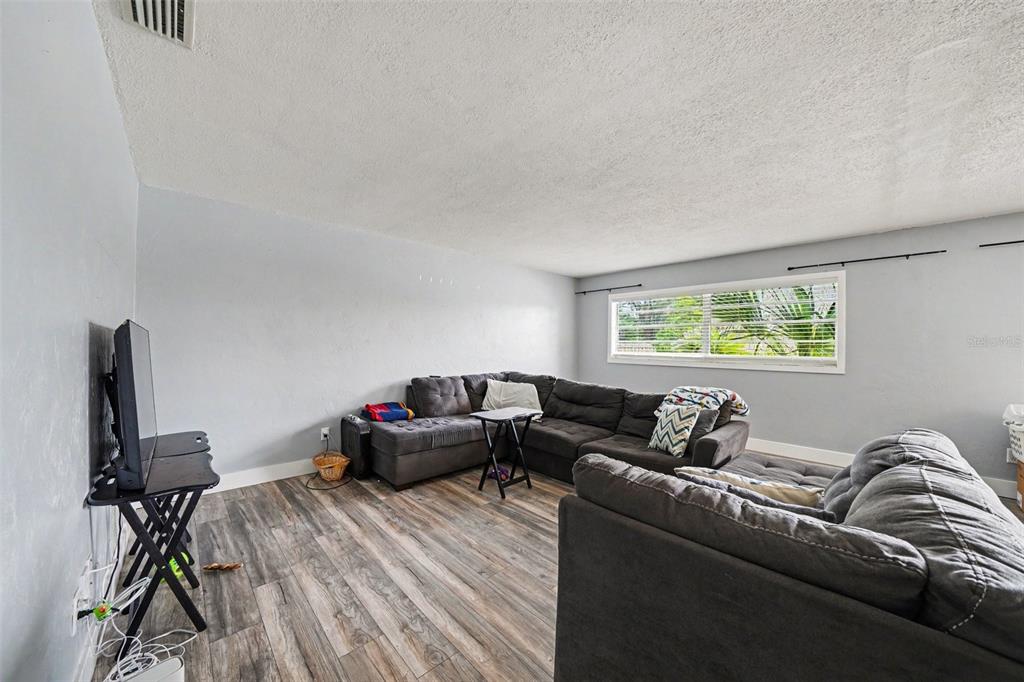 A living room features gray walls, wood-look flooring, and a large sectional sofa — 1180 BALFOUR DRIVE, DELTONA, FL