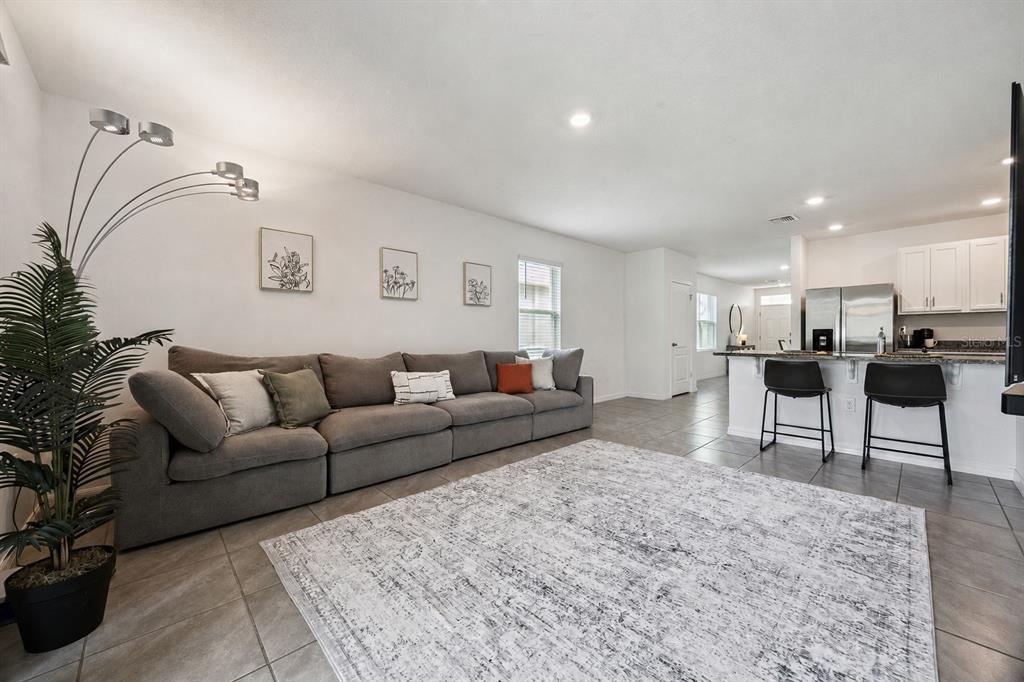 A living room with a gray sectional sofa, area rug, and an open kitchen island — 3624 SUNGROVE CIRCLE, SANFORD, FL