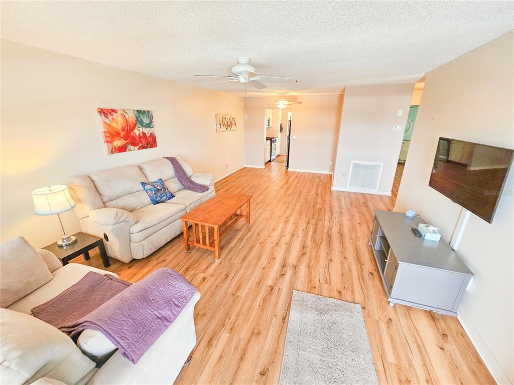 A living room features light wood-look flooring, two beige sofas, a wooden coffee table, and a television — 2960 S 59TH STREET UNIT 311, GULFPORT, FL