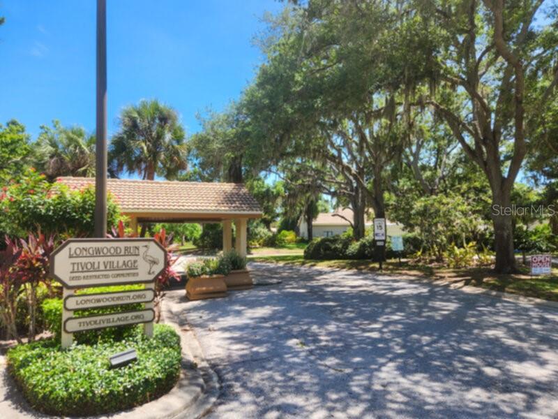 A sign for Longwood Run Tivoli Village stands at the entrance to a tree-lined community — 4700 TIVOLI AVENUE, SARASOTA, FL