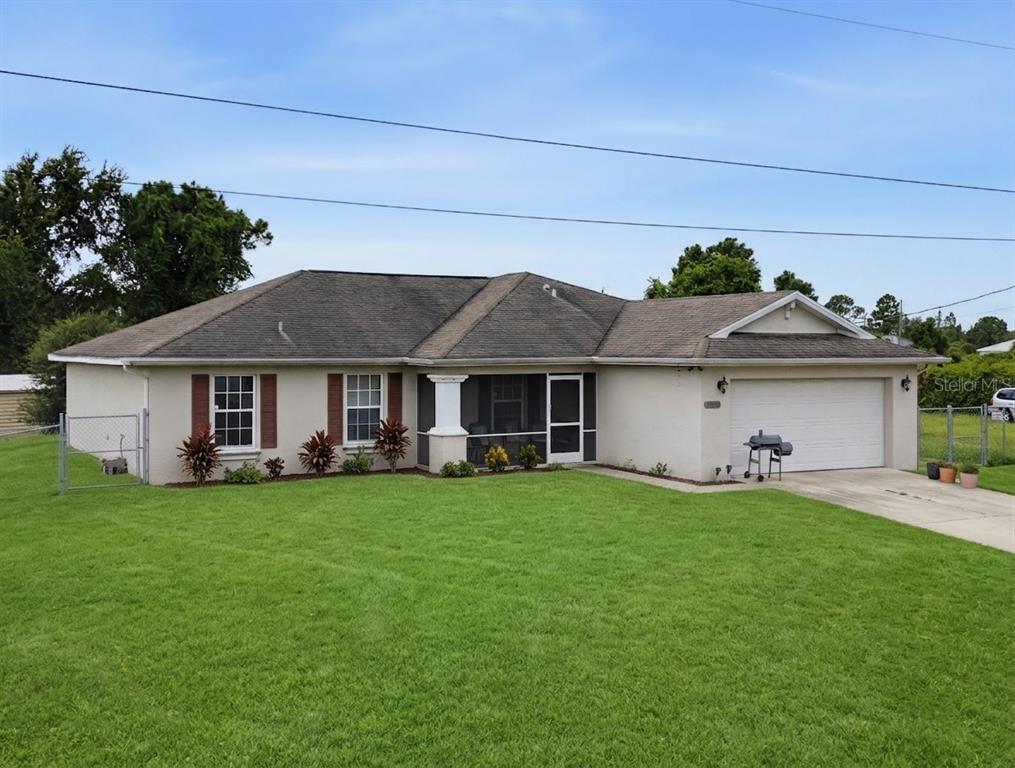 A single-story house with a beige stucco exterior, a shingled roof, and a two-car garage — 3109 64TH STREET W, LEHIGH ACRES, FL