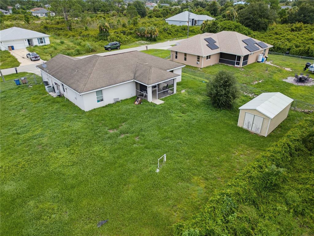 An aerial view shows two suburban houses with large grassy backyards and a storage shed — 3109 64TH STREET W, LEHIGH ACRES, FL