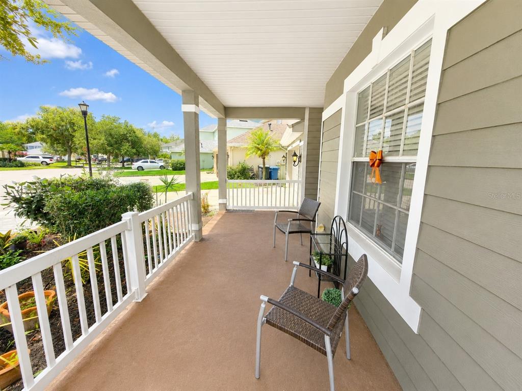 A covered front porch features a concrete floor, white railings, and two wicker chairs — 9305 MANDRAKE COURT, TAMPA, FL